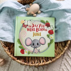 The book cover for Day You Were Born In June. A playful, illustrated mouse sat down surrounded by roses, daisies, and butterflies.