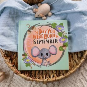 The book cover for Day You Were Born In September. A playful, illustrated mouse sat down surrounded by acorns, sycamore and aster flowers.